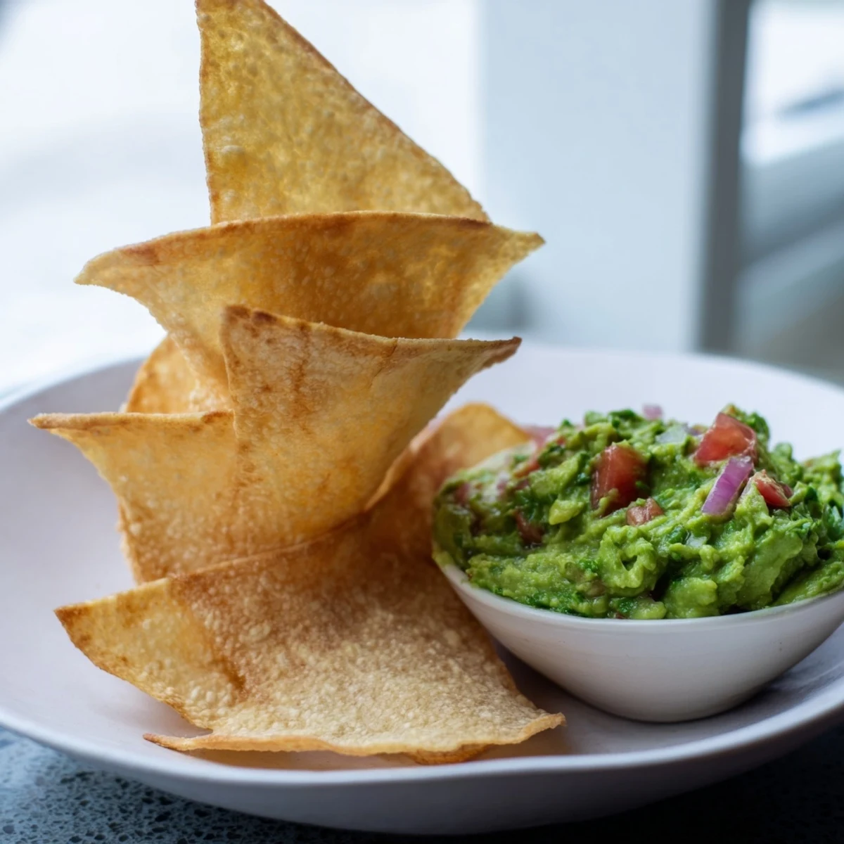 Golden-brown baked pita chips and a vibrant bowl of guacamole, a perfect, flavorful snack.
