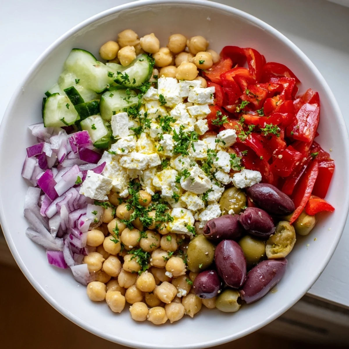 Freshly tossed Mediterranean Chickpea and Feta Bowl showcasing colorful vegetables, olives, and vegan feta.