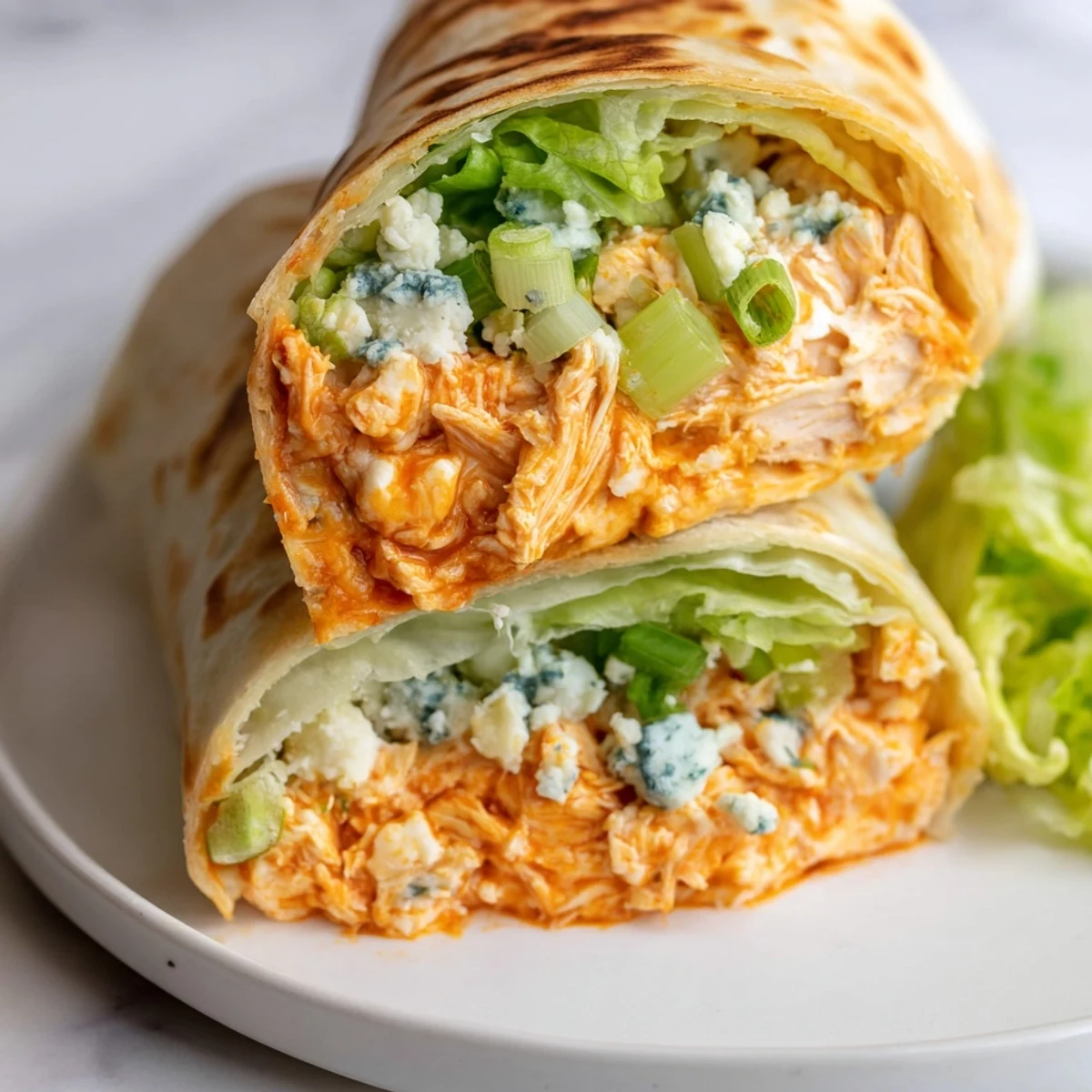 A close-up shot of a Buffalo Chicken Dip Wrap, showing a flavorful filling inside a grilled tortilla.