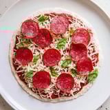 A delicious, low-carb ground beef pizza base topped with melted mozzarella and fresh basil.