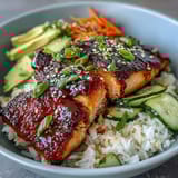 Quick teriyaki salmon bowl featuring tender glazed salmon, crisp cucumber, carrot, and avocado atop fluffy jasmine rice.