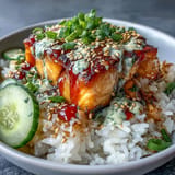 Creamy spicy mayo salmon rice bowl featuring warm rice topped with marinated salmon, crunchy cucumber, and a drizzle of zesty Sriracha mayo sauce.  