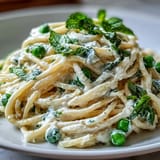 Gorgeous bowl of Lemon Ricotta Pasta with vibrant green peas and fresh mint garnish.