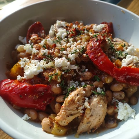 A steaming bowl of white bean and roasted red pepper chicken stew, garnished with fresh parsley.