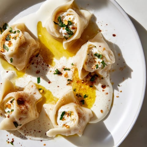 Steaming Turkish cheesy manti dumplings topped with garlicky yogurt and vibrant spiced butter.