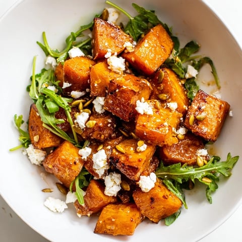Roasted Sweet Potato Salad with golden caramelized cubes, peppery arugula, and creamy feta drizzled in honey-lime dressing.
