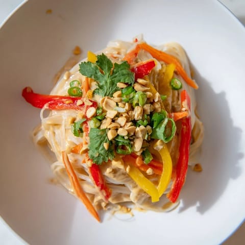 Delicious Spicy Peanut Noodles, garnished with peanuts and cilantro, offering a flavorful and satisfying vegetarian dish.