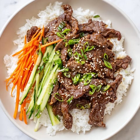 Steaming Bulgogi beef bowl showcases tender beef, colorful veggies, and a sprinkle of sesame seeds.