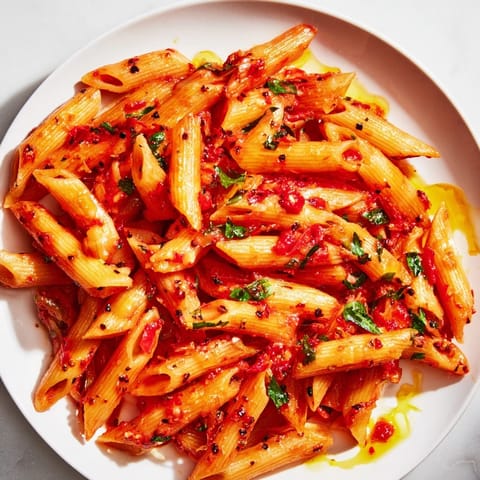 A close-up of penne all'arrabbiata, showcasing the glossy sauce and fresh parsley garnish.