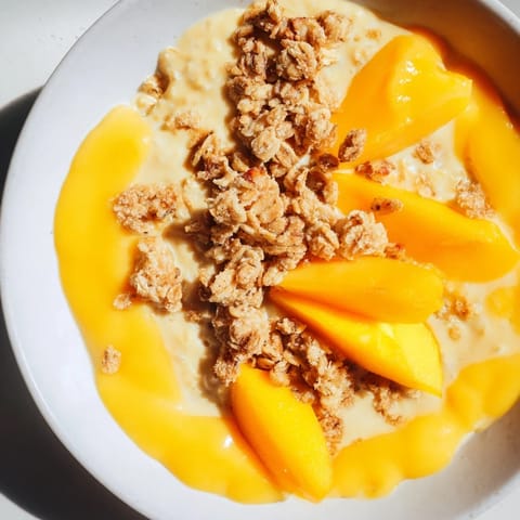 A refreshing breakfast idea: creamy Mango Blended Overnight Oats, layered with crunchy granola in a jar.