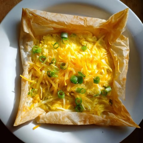 A close-up view shows a delicious Rice Paper Egg & Cheese Fold with visible green scallions.