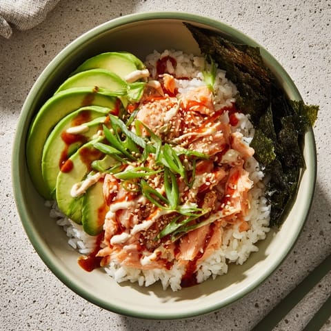 Fluffy white rice topped with tender salmon, sliced green onions, and sesame seeds in a bowl ready to be assembled.