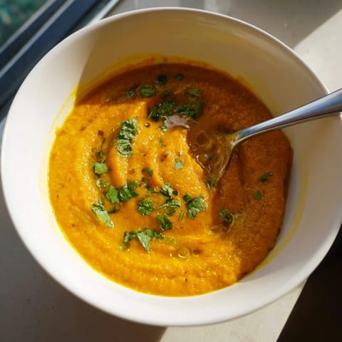 A steaming bowl of butternut squash and lentil soup with a swirl of olive oil.