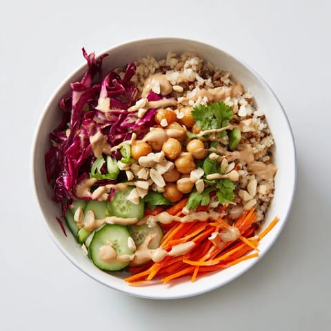 Close-up view of a Peanut Chickpea Rice Bowl, featuring colorful shredded carrots, cabbage, and a drizzle of peanut dressing.