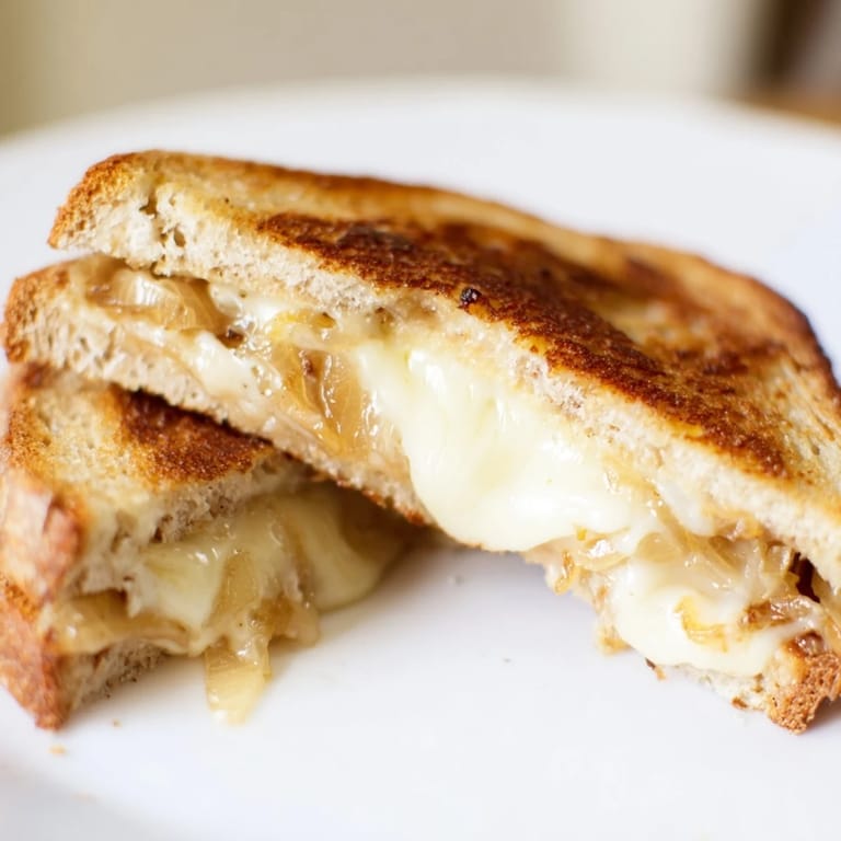 Melted sharp white cheddar and sweet onions peek from buttery, crispy slices of grilled cheese.